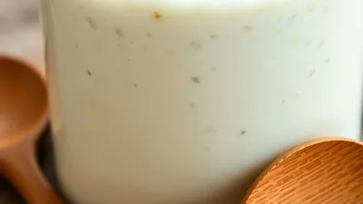 Blubbernder Sauerteig-Starter im Glas mit Holzlöffel.